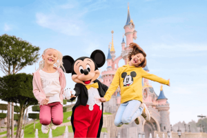 Children jumping with Mickey Mouse in front of a castle at Disneyland Paris