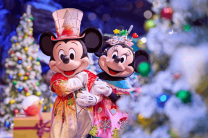 Mickey and Minnie Mouse wearing festive holiday outfits posing in front of snow-flocked Christmas trees