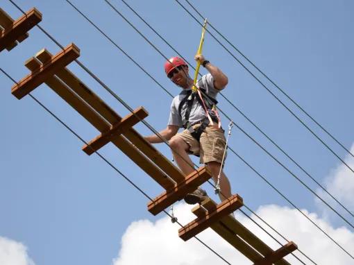 Man traversing swinging bridge on the Sceamin Gator Zip Line course at Gatorland in Florida