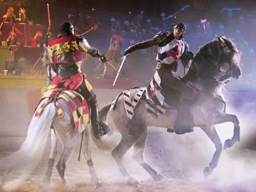 Knights with swords on horseback at Knights riding horses in the arena at Medieval Times Orlando Dinner Show & Tournament