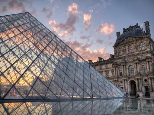 The glass pyramid of The Louvre museum in front of a sunset