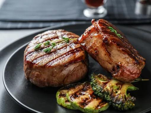 Two steak filets on a plate with grilled green vegetables