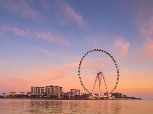 Ain Dubai silhouette at sunset, with vibrant sky and the observation wheel in the distance