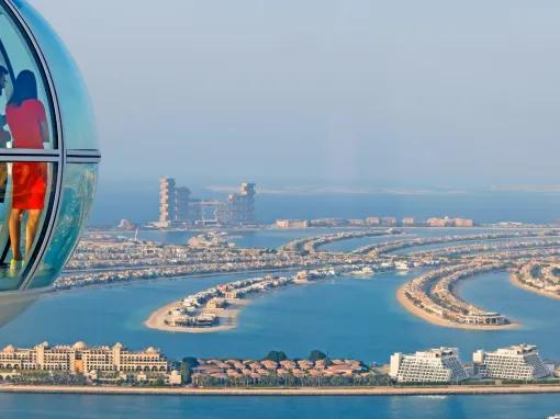 A couple enjoying the view of The Palm from a capsule on Ain Dubai, with stunning cityscape in the background