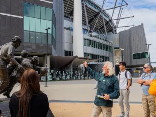 Tour guide showing a statue to a group of guests at the MCG Forecourt during the Melbourne City Discovery Tour