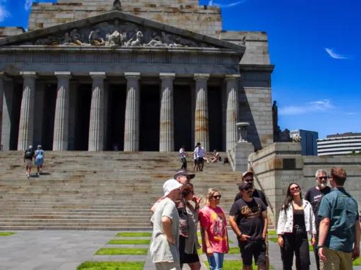 Tour group smiling and standing outside the Shrine of Remembrance during the Melbourne City Discovery Tour