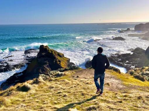 Person standing on a cliff edge at the Nobbies, overlooking stunning ocean and coastal scenery