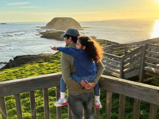 Father carrying child on his back while watching the sunset over the Nobbies coastline