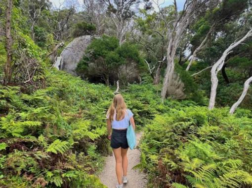 Woman walking toward Tidal River surrounded by natural bushland at Wilsons Promontory