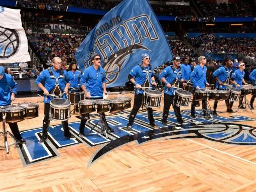 Drumline performing with big flags on the court at an Orlando Magic game