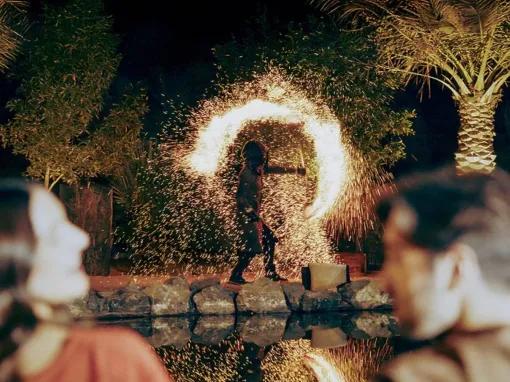 Couple watching a fire dancer perform at a desert camp at night