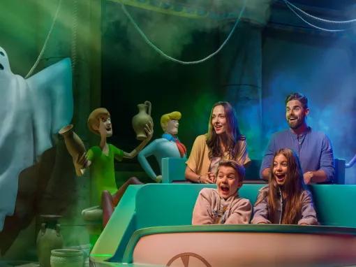 Guests enjoying the Scooby-Doo: The Museum of Mysteries ride at Warner Bros. World Abu Dhabi, laughing in a ride vehicle as a friendly ghost figure floats nearby.
