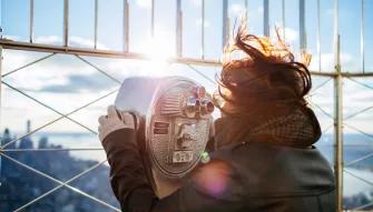 Woman looking through a telescope at the Empire State Building Observatory