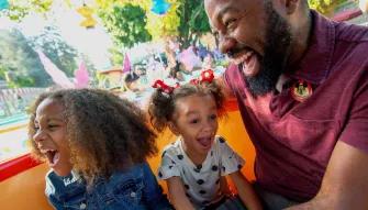father and daughters enjoying a ride at Disneyland in California