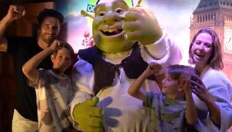Eine lachende Familie steht mit der Filmfigur Shrek in Shrek's Adventure