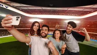 A happy family smiling while taking a selfie at the Bernabéu Experience in Real Madrid World Dubai