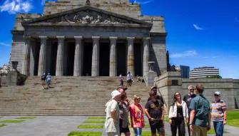 Melbourne City Discovery Tour Tour group smiling and standing outside the Shrine of Remembrance during the Melbourne City Discovery Tour