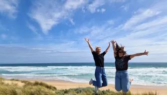 Phillip Island Express Tour Two women jumping with arms raised at Cape Woolamai with the beautiful ocean in the background