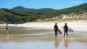 Wilsons Promontory Day Tour People walking with surfboards along the white sands of Squeaky Beach at Wilsons Promontory