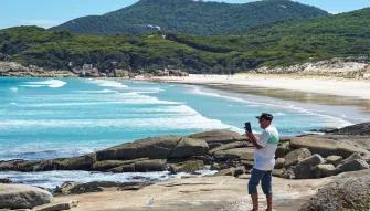 Wilsons Promontory Day Tour Person taking a photo from the Squeaky Beach lookout, capturing beautiful coastal views at Wilsons Promontory
