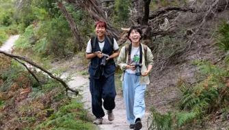 Wilsons Promontory Day Tour Two happy people walking through lush woodlands on a guided hike at Wilsons Promontory