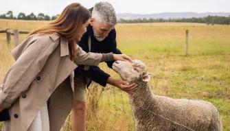 Two people petting a sheep during a farm visit on the Yarra Valley Grazing Tour