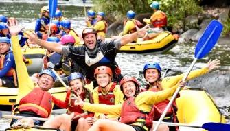 A group of happy people having fun on a raft at Barron River Rafting