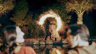 Couple watching a fire dancer perform at a desert camp at night
