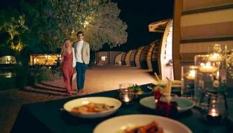 ouple walking toward a candlelit dinner setup at a luxury desert camp