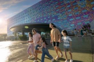 Parents with their three kids walking together in the sun in front of Universal Stella Nova Resort