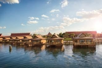 Luxurious bungalows at Disney's Polynesian Village Resort built over water, sitting underneath a sunny blue sky