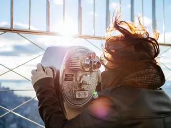 Woman looking through a telescope at the Empire State Building Observatory