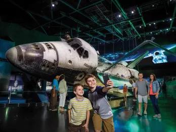 Boys taking a selfie in front of Space Shuttle Atlantis at Kennedy Space Center in Florida