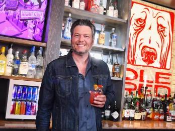 Blake Shelton holding a glass of sangria behind a bar