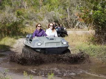 Orlando Revolution Adventures Two people sat side by side in a mucky duck 4x4 vehicle driving into water