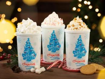 Three hot chocolates topped with cream in cups with Christmas trees and the writing "SeaWorld's Christmas Celebration" written on them