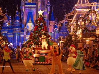 Mickey's Very Merry Christmas Party Mickey Mouse standing in front of a Christmas Tree on a parade float. Characters such as Peter Pan, Donald Duck and Pluto dance in front of it