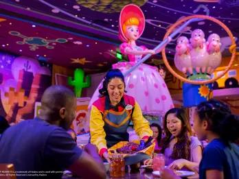 Roundup Rodeo BBQ A server bringing a basket full of food to a table of 2 adults and 2 children. There is Toy Story theming in the background including a figure of Bo Peep