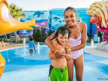 A young boy and girl standing in a splash pad themed after Finding Nemo