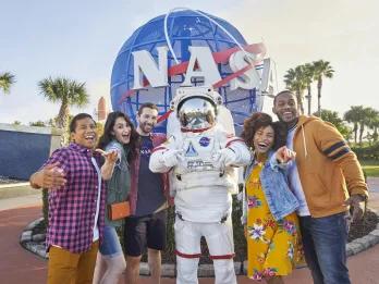 Kennedy Space Center A group of 5 adults posing in front of the NASA logo with an astronaut