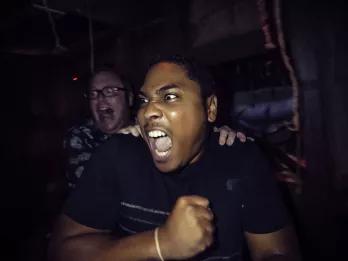 Two men in a haunted house screaming at something to their right