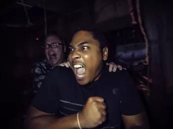 Halloween Horror Nights Two men in a haunted house screaming at something to their right