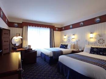 A nautical themed hotel room with two double beds and a dresser