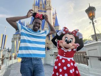 A man wearing Minnie ears standing with Minnie Mouse in front of Cinderella Castle