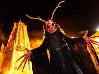 Halloween Horror Nights Hollywood 2023 A blood-covered figure with long fingers and horns and large eye sockets looking down at the camera