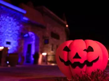 A jack-o'-lantern on the ground in front of a stone building at night
