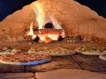 Pizza in Orlando 5 pizzas cooking in a large wood-fired pizza oven