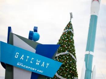 The Gateway Deep Space Launch Complex sign in front of a large Christmas tree 