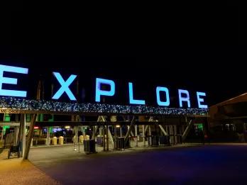 An entrance gate decorated with Christmas decorations and "EXPLORE" lit up with blue lights