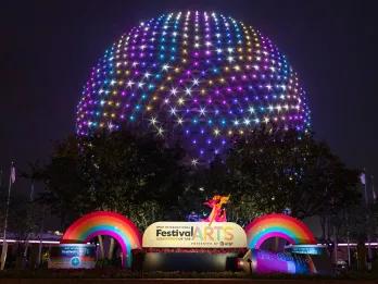 EPCOT Festival of the Arts Spaceship Earth lit up in rainbow colours behind a sign reading Festival of the Arts